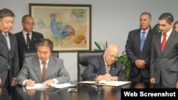 El ministro de Economía cubano Ricardo Cabrisas y el embajador japonés Masaru Watanabe firman el acuerdo.
