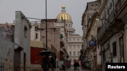 Bicitaxis circulando por una calle empapada por la lluvia con el Capitolio al fondo, en La Habana, Cuba, el 28 de septiembre de 2026. (REUTERS/Ricardo Arduengo)