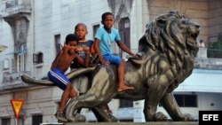 Varios niños juegan sobre uno de los leones del Paseo del Prado de La Habana (Cuba)