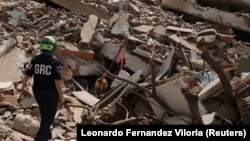Rescatista y su perro buscan víctimas entre los escombros de un edificio en La Guaira, este 28 de junio de 2026. (REUTERS/Leonardo Fernandez Viloria)