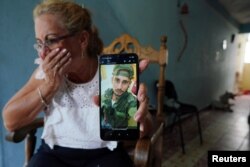 Marilin Vinent muestra una foto de su hijo Dannys Castillo vestido con uniforme militar. REUTERS/Alexandre Meneghini