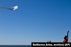 ARCHIVO - Dan Watman y un niño vuelan una cometa hecha de bolsas de plástico y periódicos, cerca de la división fronteriza entre Estados Unidos y México, en Tijuana.