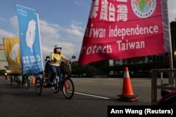 Personas en bicicletas con banderas que apoyan la independencia de Taiwán asisten a una manifestación contra la invasión rusa de Ucrania, en Taipei, Taiwán, el 13 de marzo de 2022. (Archivo REUTERS/Ann Wang)