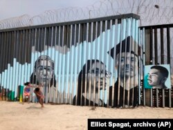 ARCHIVO - Niños juegan frente a un mural de la artista Lizbeth De La Cruz Santana, en el lado mexicano del muro fronterizo en Tijuana, México.