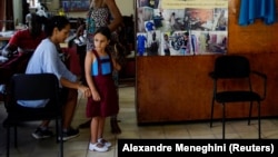 Una niña se prueba un uniforme escolar en una tienda de ropa reciclada en La Habana. (REUTERS/Alexandre Meneghini)