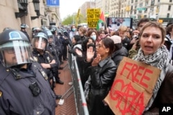 Policías con equipo antimotines montan guardia mientras manifestantes corean consignas afuera del campus de la Universidad de Columbia, el jueves 18 de abril de 2024, en Nueva York. (AP Foto/Mary Altaffer)