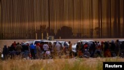 Migrantes cerca del muro fronterizo después de cruzar el río Bravo con la intención de entregarse a los agentes de la Patrulla Fronteriza de los Estados Unidos. (REUTERS: José Luis González).