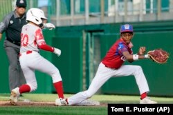 Shuma Tachibana (10), de Japón, quieto en primera base junto al primera base cubano Heikel Reyes. (AP/Tom E. Puskar)