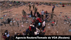Migrantes intentan cruzar una valla de alambre de púas desplegada para impedir el cruce de migrantes a EEUU, a orillas del río Bravo, en la frontera con México, visto desde Piedras Negras, Coahuila, el 21 de diciembre de 2023.