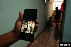 Un familiar muestra una foto de Dannys Castillo (C), con otros cubanos en Rusia. REUTERS/Alexandre Meneghini
