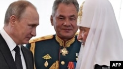 (Izq. a Der.) El presidente ruso Vladimir Putin, el ministro de Defensa ruso Sergei Shoigu y el patriarca de Moscú Kirill. San Petersburgo, 30 de julio de 2017.