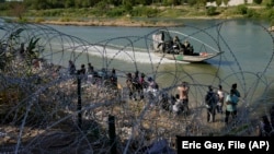 Inmigrantes que cruzaron a Estados Unidos desde México se encuentran con alambre de púas a lo largo del Río Grande, en Eagle Pass, Texas. (AP/Eric Gay, File)