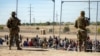 Migrantes esperan junto a una valla fronteriza bajo la vigilancia de la Guardia Nacional de Texas el 10 de mayo de 2023 para ingresar a El Paso, Texas. (AP/Andrés Leighton)