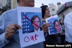 Palestinos muestran imágenes tachadas en rojo del secretario de Estado de Estados Unidos, Antony Blinken, en protesta por su visita a Ramallah, en la ocupada Cisjordania.