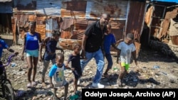 Jimmy Chérizier, un expolicía de élite conocido como Barbacue y que ahora dirige una federación de pandillas, camina de la mano de varios niños en una visita al distrito de La Saline en Puerto Príncipe, Haití, el 24 de enero de 2023.