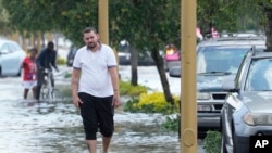 Los peatones caminan en una calle inundada el jueves 13 de abril de 2023 en Fort Lauderdale, Florida. (AP Photo/Marta Lavandier)