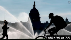 ARCHIVO - El Capitolio se ve mientras los rociadores de agua empapan el National Mall en una calurosa mañana de verano en Washington, el 15 de julio de 2022.