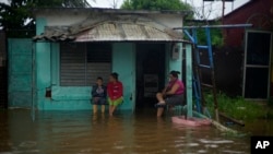 Residentes contemplan el frente de su vivienda lleno de agua, en Batabanó. 