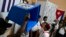 Una autoridad electoral muestra una urna vacía antes de iniciar los comicios legislativos de este domingo en Cuba. (ADALBERTO ROQUE / AFP)