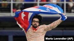 El escritor y periodista Carlos Manuel Alvarez se lanza al terreno en el LoanDepot Park de Miami con la bandera cubana en alto, en protesta contra el régimen de La Habana. (AP/Marta Lavandier)