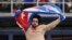 El escritor y periodista Carlos Manuel Alvarez se lanza al terreno en el LoanDepot Park de Miami con la bandera cubana en alto, en protesta contra el régimen de La Habana. (AP/Marta Lavandier)