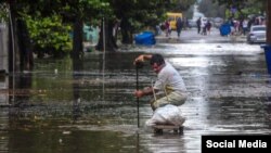 Un vecino destupe una alcantarilla en una calle inundada de El Vedado. (Facebook Canal Caribe)