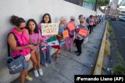 Votantes, algunos con un cartel de apoyo a la candidata presidencial de la oposición Xóchitl Gálvez, hacen fila afuera de un colegio electoral durante las elecciones generales en la Ciudad de México, el 2 de junio de 2024. (AP/Fernando Llano)