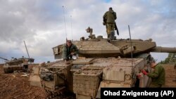 Soldados israelíes trabajan en un tanque en un puesto del ejército cerca de la frontera con Gaza, en el sur de Israel, el 27 de noviembre de 2023. (AP Foto/Ohad Zwigenberg)
