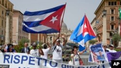 Miembros de la comunidad cubana en Italia ondean banderas del país y cantan consignas contra el presidente de Cuba, Miguel Díaz-Canel durante su visita al Vaticano. (AP/Domenico Stinellis)