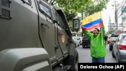 Un partidario del exvicepresidente ecuatoriano Jorge Glas protesta mientras un vehículo militar lo transporta desde el centro de detención en el que estuvo detenido tras su arresto en la embajada de México en Quito, Ecuador.