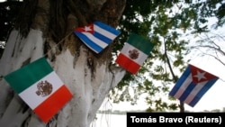 Banderas cubanas y mexicanas colgadas de un árbol. (Tomás Bravo/Reuters.)