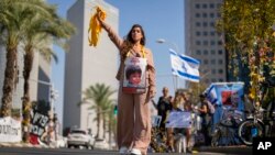 Una mujer, con la fotografía de un niño que fue tomado como rehén durante el ataque sin precedentes de Hamás en Israel, entrega listones amarillos a los automovilistas en el centro de Tel Aviv. (AP Foto/Francisco Seco)