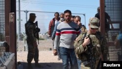 Un grupo de migrantes escoltados por soldados estadounidenses, luego de que las autoridades estadounidenses les permitieran ser llevados a un centro de procesamiento de CBP en El Paso, para procesar su solicitud de inmigración. Foto: Reuters.