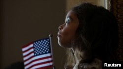 Un niño escucha el himno nacional durante la ceremonia de naturalización, en
Boston. Los cubanos ocuparon el quinto puesto en recibir la ciudadania de EEUU en 2023. 