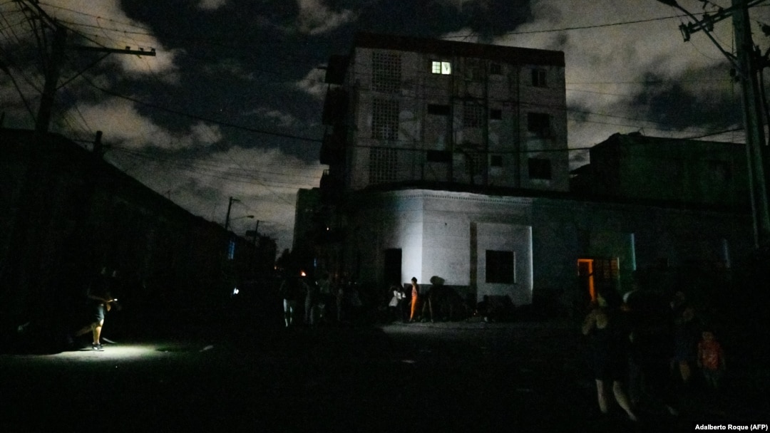 Vecinos se congregan en el exterior de una vivienda en medio del apagón. Adalberto Roque/AFP)