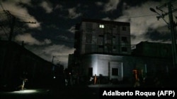 Vecinos se congregan en el exterior de una vivienda en medio del apagón. (Adalberto Roque/AFP).
