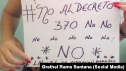 La activista Grethel Rams Santana sostiene un cartel en contra del Decreto ley 370. 
