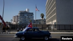 Un automóvil antiguo pasa por la Embajada de los Estados Unidos con una bandera cubana. (REUTERS/Alexandre Meneghini)