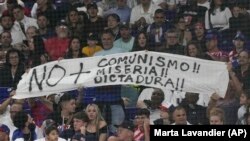Asistentes a la semifinal del Clásico Mundial de Béisbol entre Cuba y EEUU levantan un cartel que reza "No más comunismo, miseria, dictadura!!". (AP/Marta Lavandier)