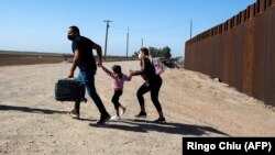 Una familia de migrantes cubanos se apresura a cruzar la frontera en Yuma, Arizona, en mayo de 2021. (Ringo Chiu/ AFP)