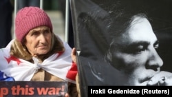 Una mujer sostiene un cartel contra la guerra en Ucrania durante una manifestación de apoyo al expresidente de Georgia encarcelado Mikheil Saakashvili, en Tbilisi, Georgia, en febrero de 2023. (REUTERS/Irakli Gedenidze)