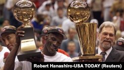 Michael Jordan y el coach de los Chicago Bulls Phin Jackson sostienen los trofeos del sexto campeonato de la NBA ganado por el equipo, en 1998. (Robert Hanashiro-USA TODAY vía Reuters)