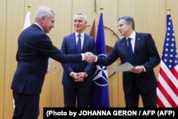 Apretón de manos del ministro de Exteriores de Finlandia, Pekka Haavisto, y el secretario de Estado de EEUU, Antony Blinken, frente a Jens Stoltenberg, secretario general de la OTAN. (AFP/Johanna Geron).