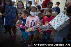 Niños sostienen regalos de Navidad donados por grupo de voluntarios «Un Juguete, Una Buena Noticia», en Caracas, Venezuela,18 de diciembre de 2020. (AP Foto/Ariana Cubillos)