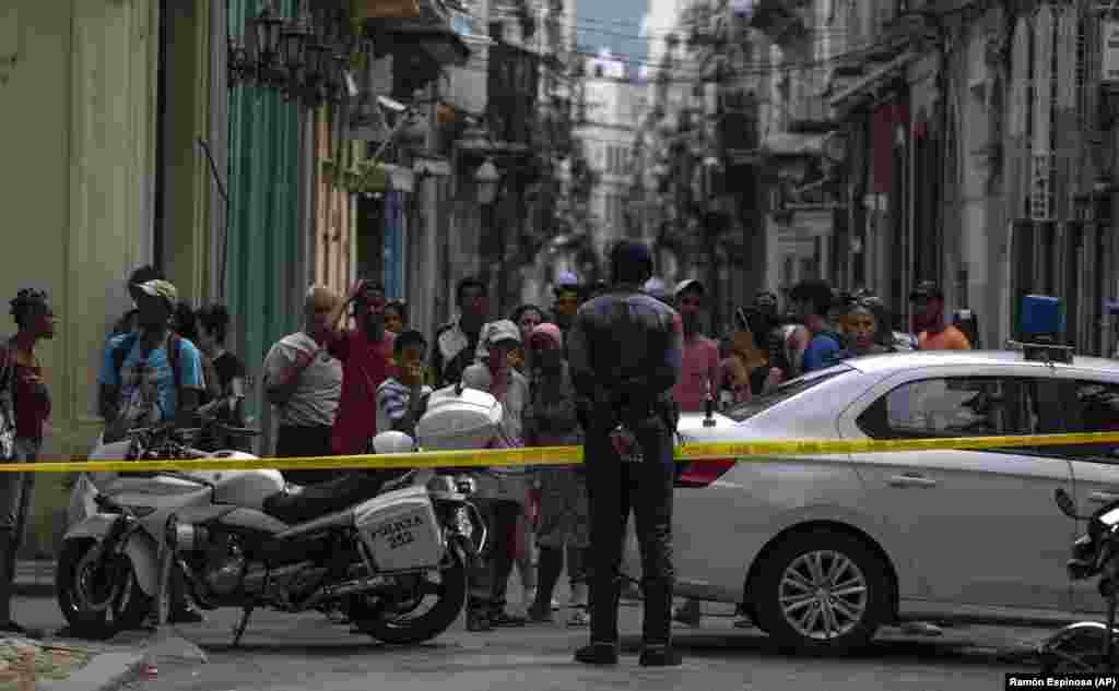 La gente observa a los bomberos limpiando los escombros del edificio que se derrumbó en La Habana Vieja. (AP/Ramón Espinosa)