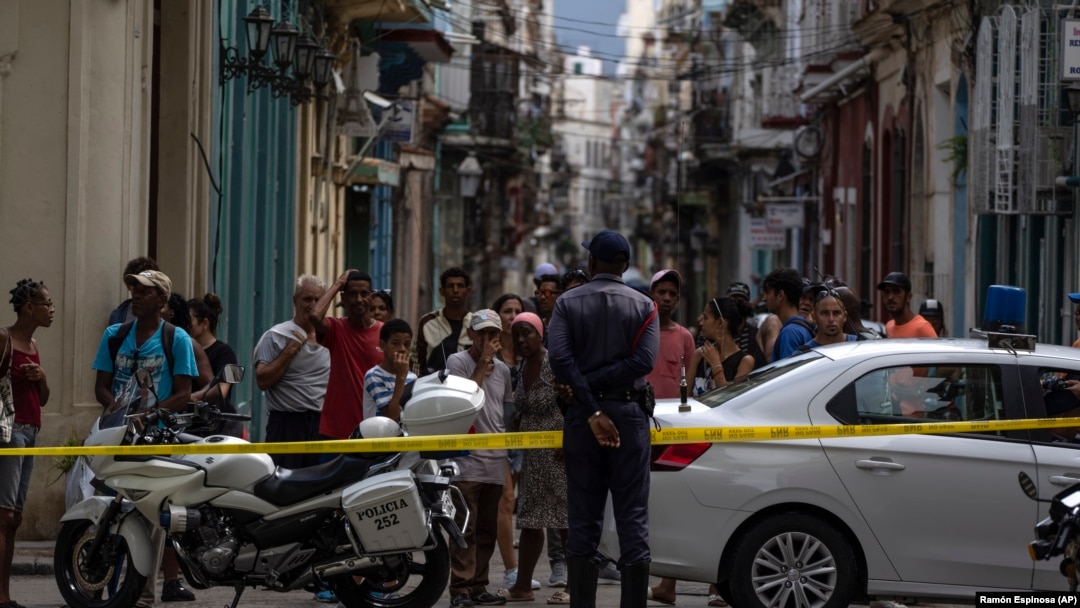 La gente observa a los bomberos limpiando los escombros del edificio que se derrumbó en La Habana Vieja. (AP/Ramón Espinosa)