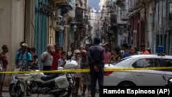 La gente observa a los bomberos limpiando los escombros del edificio que se derrumbó en La Habana Vieja. (AP/Ramón Espinosa)