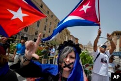 Cubanos enarbolan banderas y gritan consignas contra el gobernante cubano Miguel Díaz-Canel, en las inmediaciones del Vaticano. (AP/Domenico Stinellis)