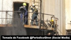 Obreros tratan de eliminar el hollín de la chimenea en la Central Termoeléctrica Antonio Guiteras.