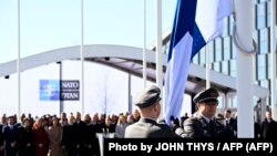 Militares de Finlandia izan la bandera nacional frente a la sede de la OTAN en Bruselas, Bélgica, el 4 de abril de 2023 (John Thys/AFP).